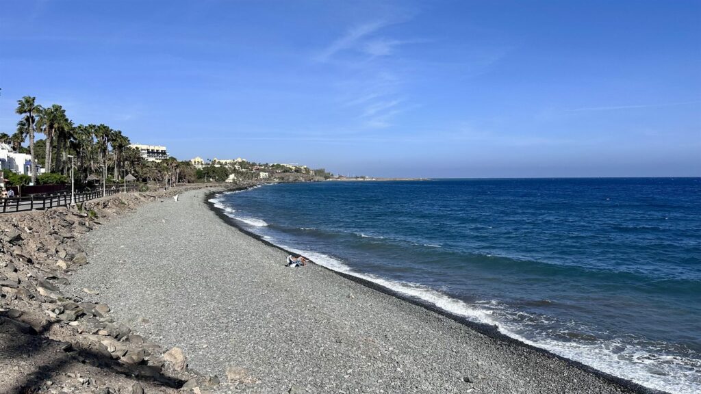Oblázková pláž Bahía Feliz s promenádou a palmami na jihu Gran Canarie