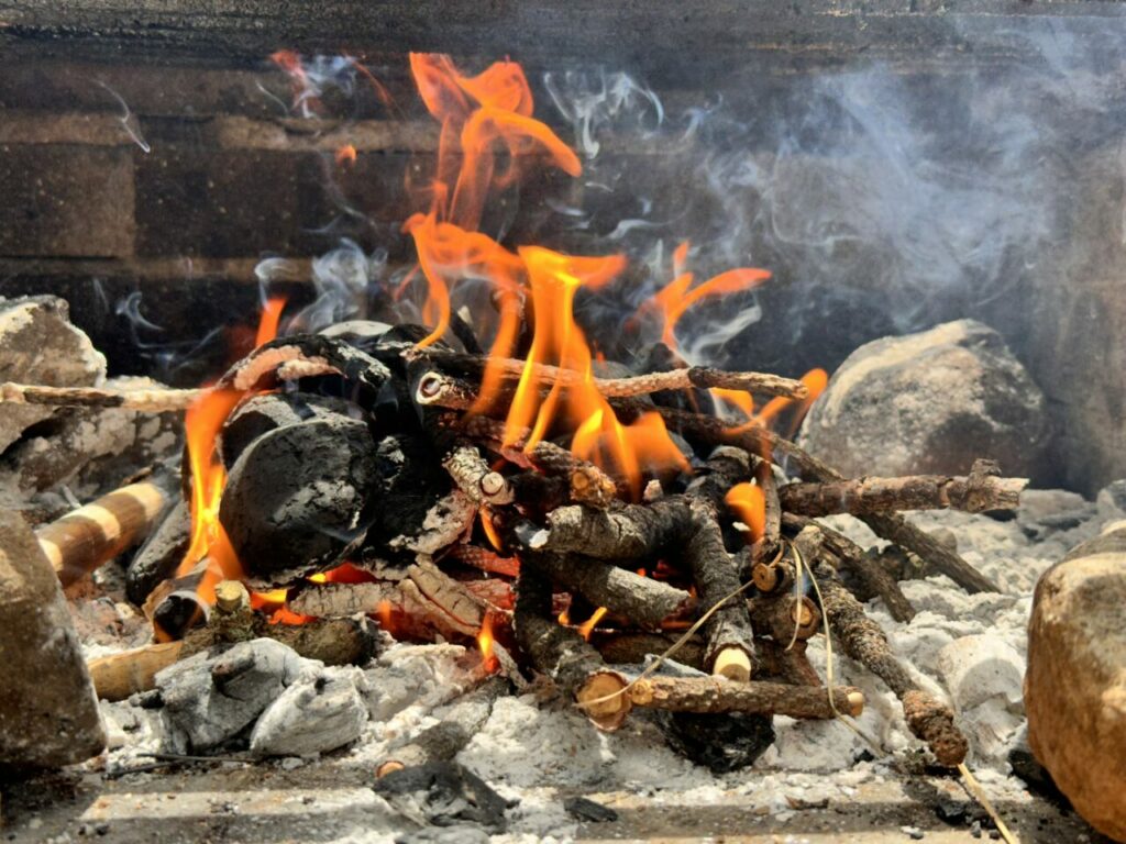 Oheň z dřevěného uhlí a třísek v kamenném grilu
